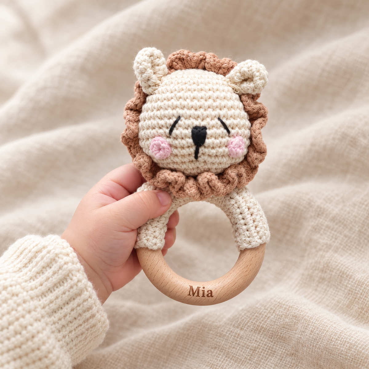Hochet en crochet personnalisé lion timide joues roses tenu par bébé, prénom gravé