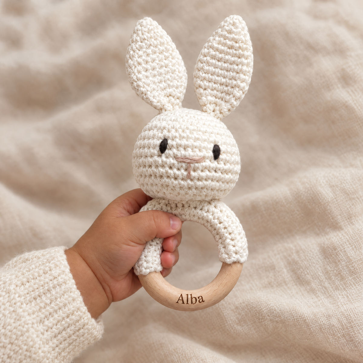 Hochet en crochet personnalisé lapin crème tenu par bébé, prénom gravé