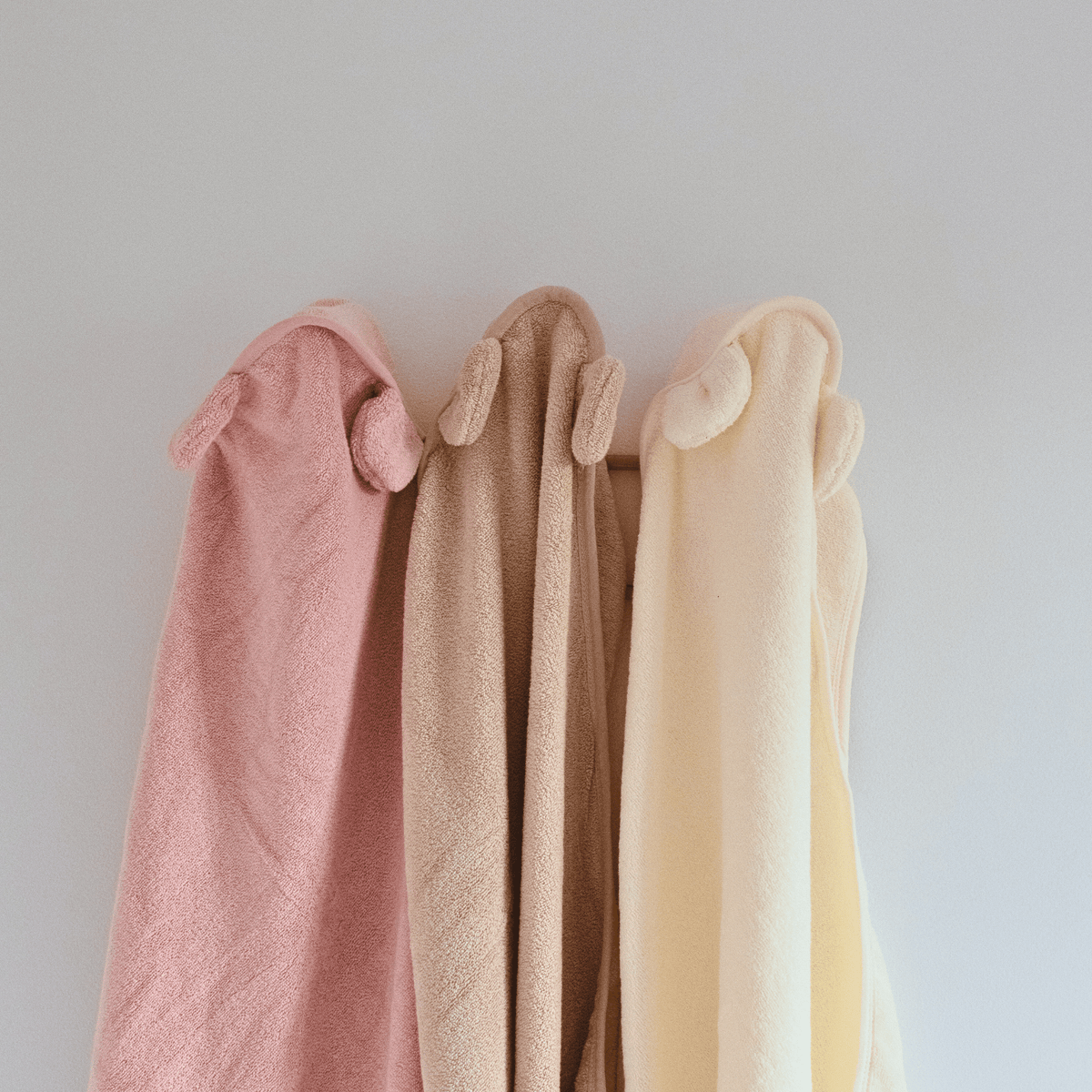 Capes de bain personnalisées avec différents prénoms, accrochées au mur