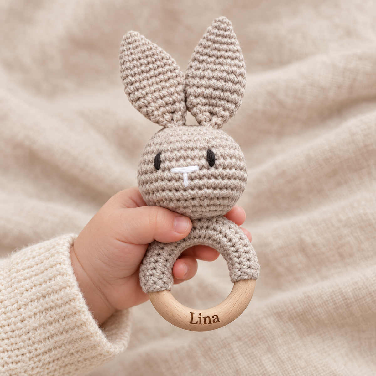 Hochet en crochet personnalisé lapin taupe tenu par bébé, prénom gravé