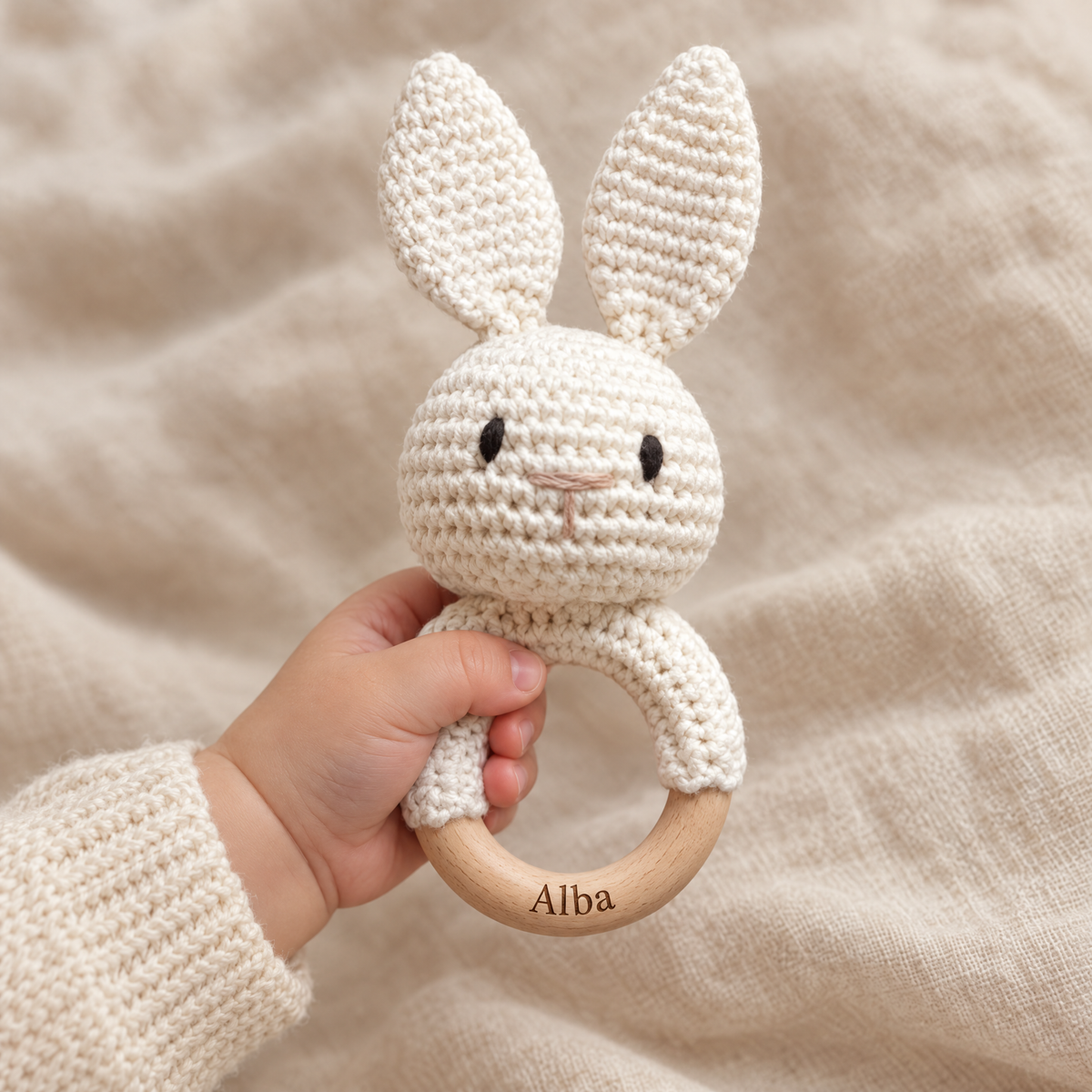 Hochet en crochet personnalisé lapin crème tenu par bébé, prénom gravé