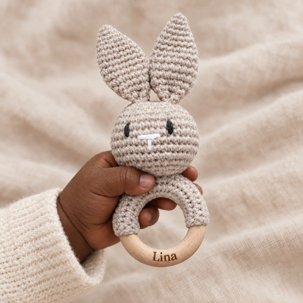 Hochet en crochet personnalisé lapin taupe tenu par bébé, prénom gravé